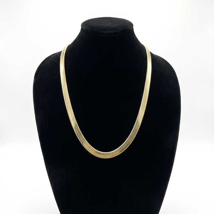 Cadena serpiente de El Rey Joyero en oro laminado 18k, diseño plano de 6mm sobre busto expositor negro.
