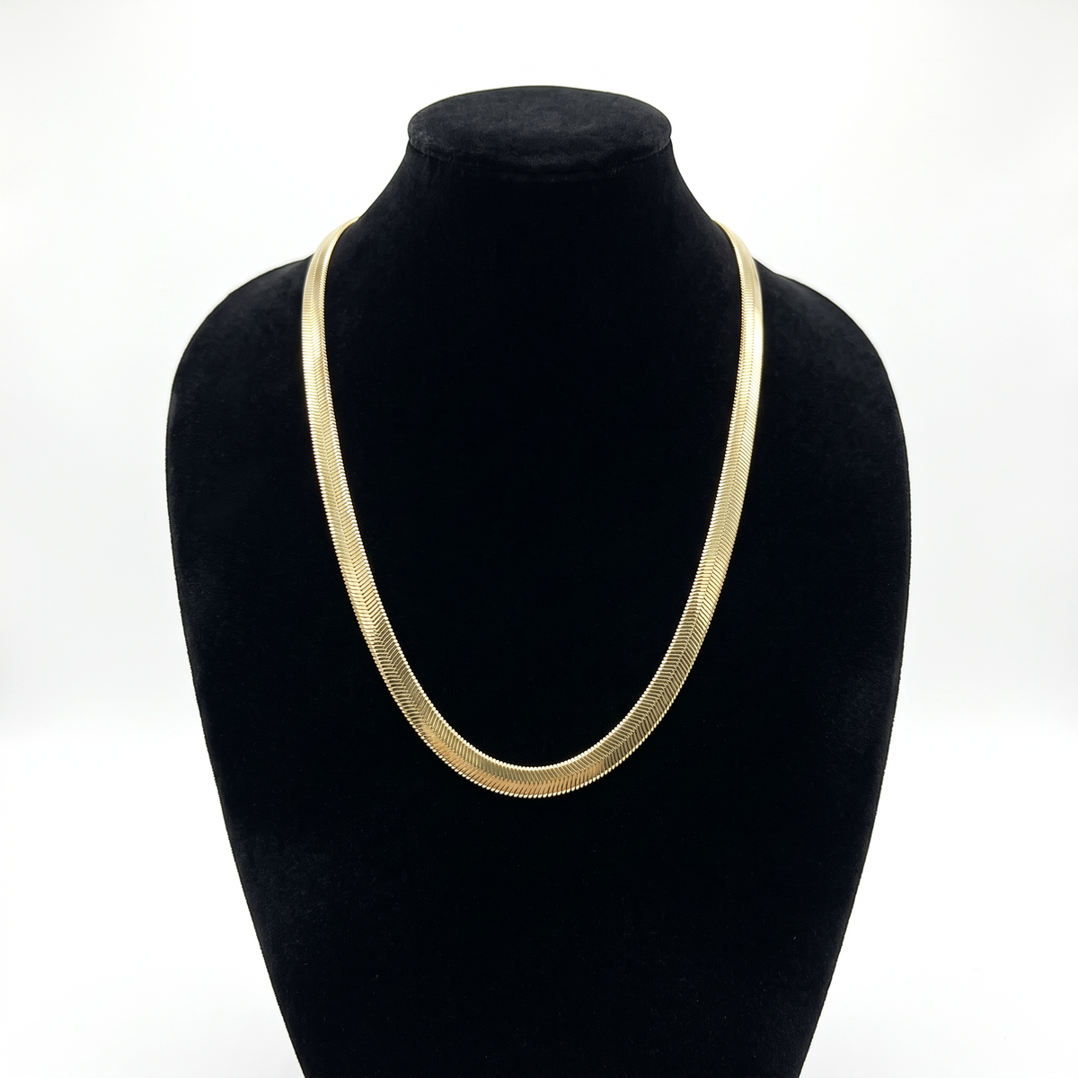 Cadena serpiente de El Rey Joyero en oro laminado 18k, diseño plano de 6mm sobre busto expositor negro.