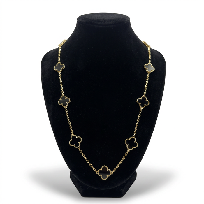 Collar El Rey Joyero de oro laminado 18k con dijes de trébol y piedra ónix negra sobre busto expositor negro.