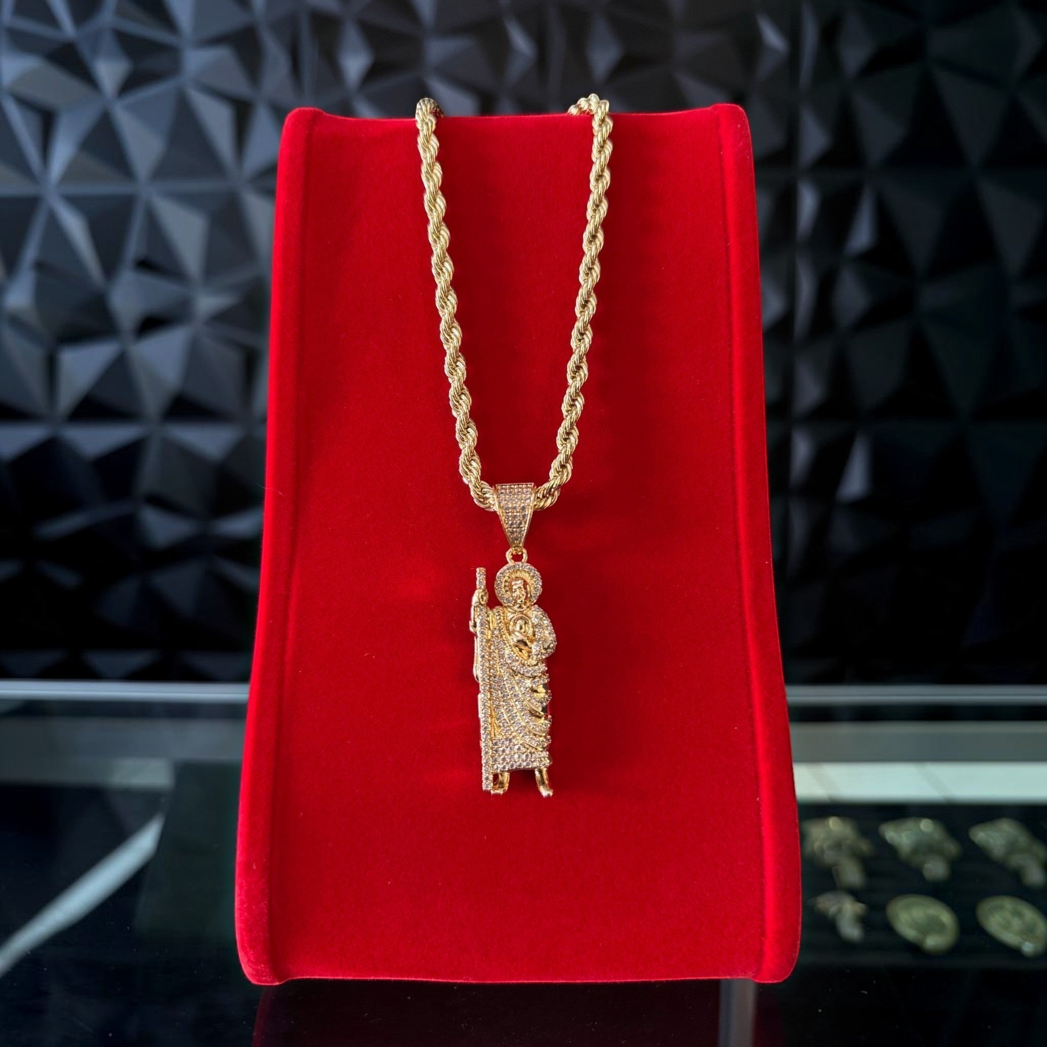 Cadena y dije de San Judas adiamantado en oro laminado 18k de El Rey Joyero sobre exhibidor rojo
