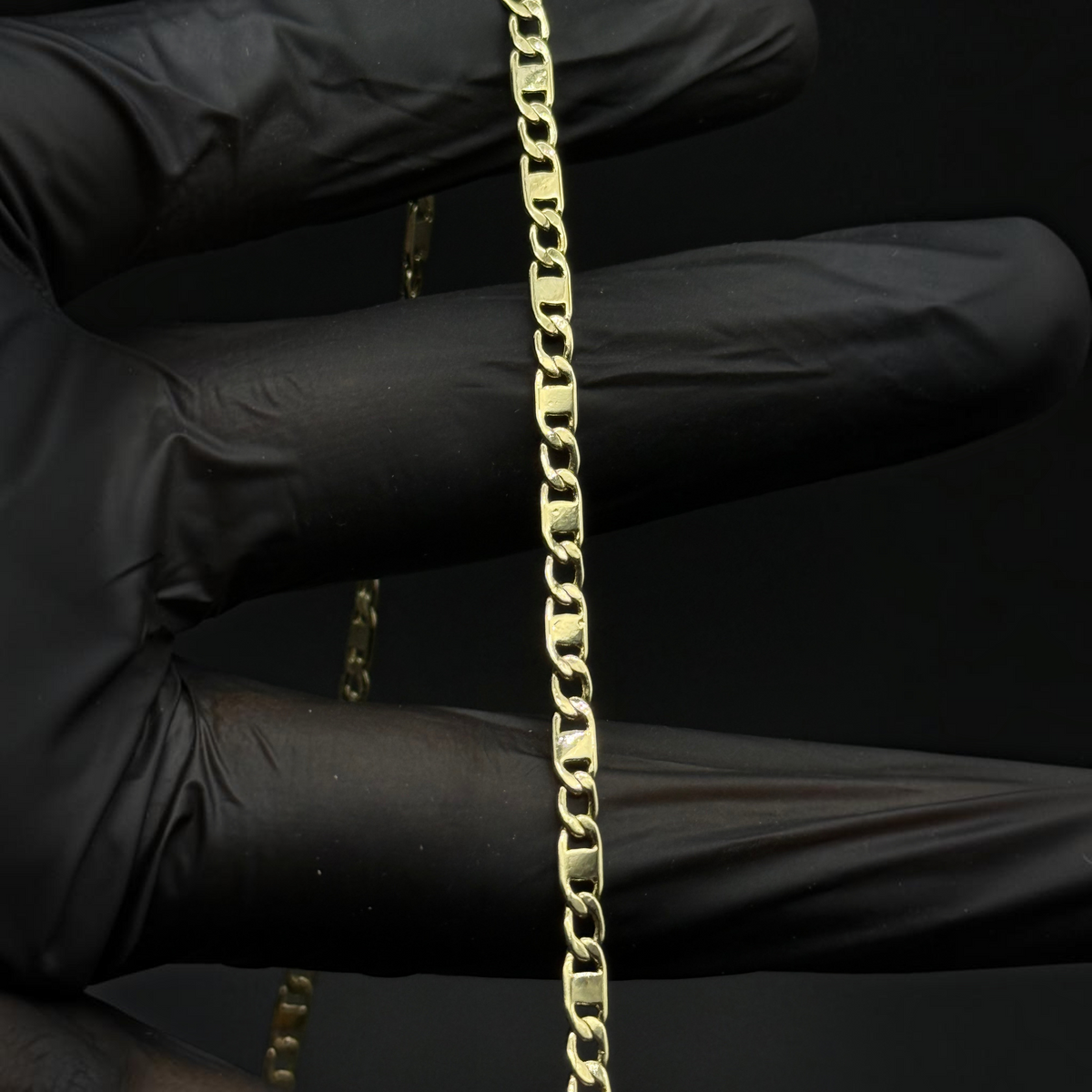 Cadena espejo delgada de El Rey Joyero en oro laminado 18k con eslabones planos y brillantes sobre fondo negro