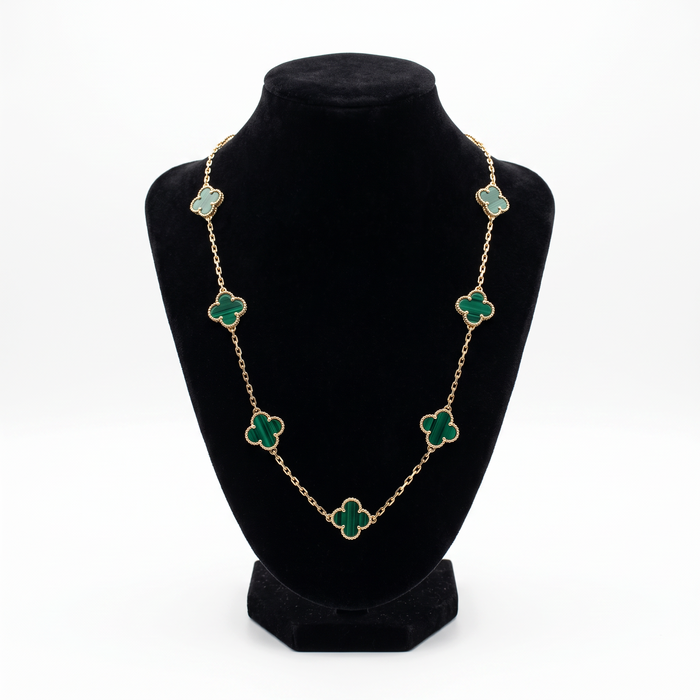Collar El Rey Joyero estilo VC con eslabones dorados y dijes de trébol en piedra verde sobre busto expositor negro.