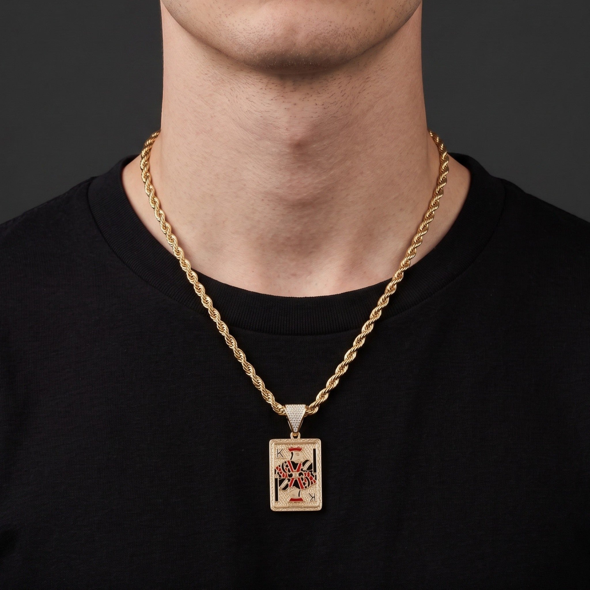 Dije de carta Rey de El Rey Joyero con cadena de oro tipo cuerda sobre camiseta negra
