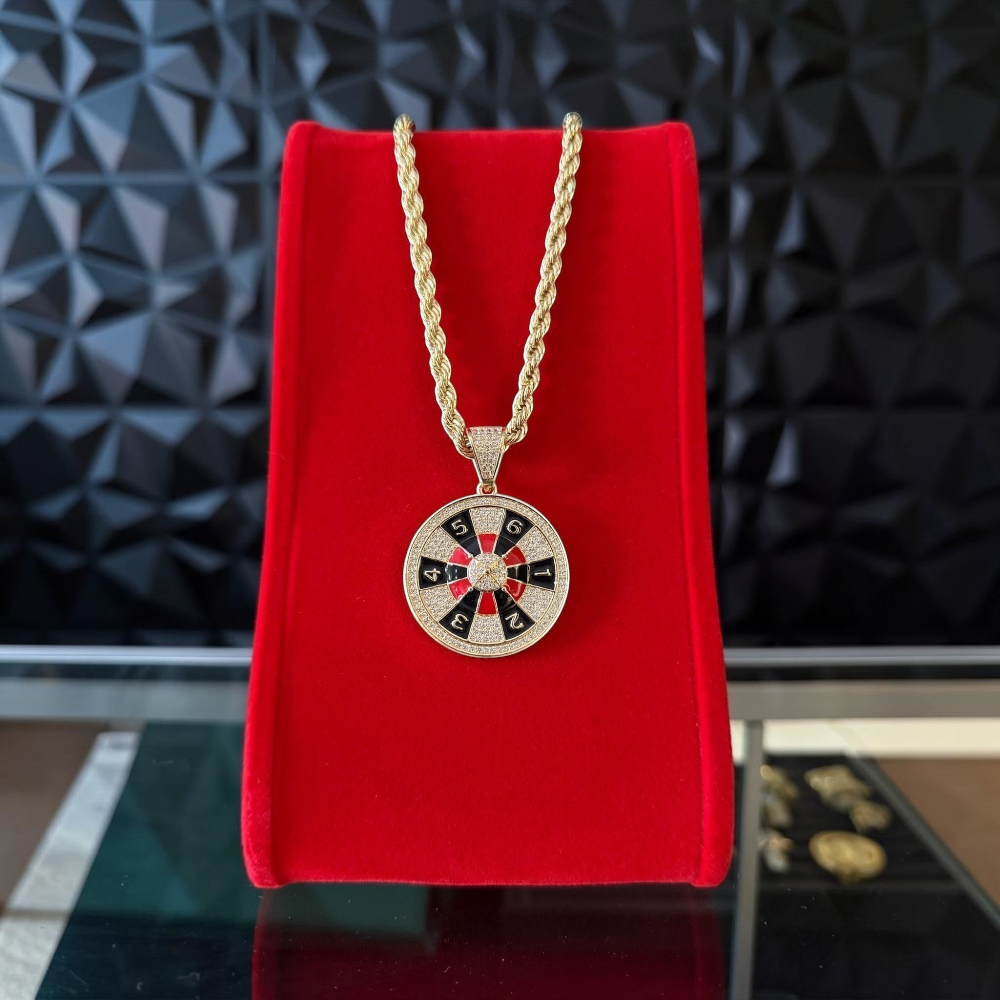 Set de cadena y dije de ruleta con detalles en esmalte rojo y negro de El Rey Joyero sobre expositor de terciopelo