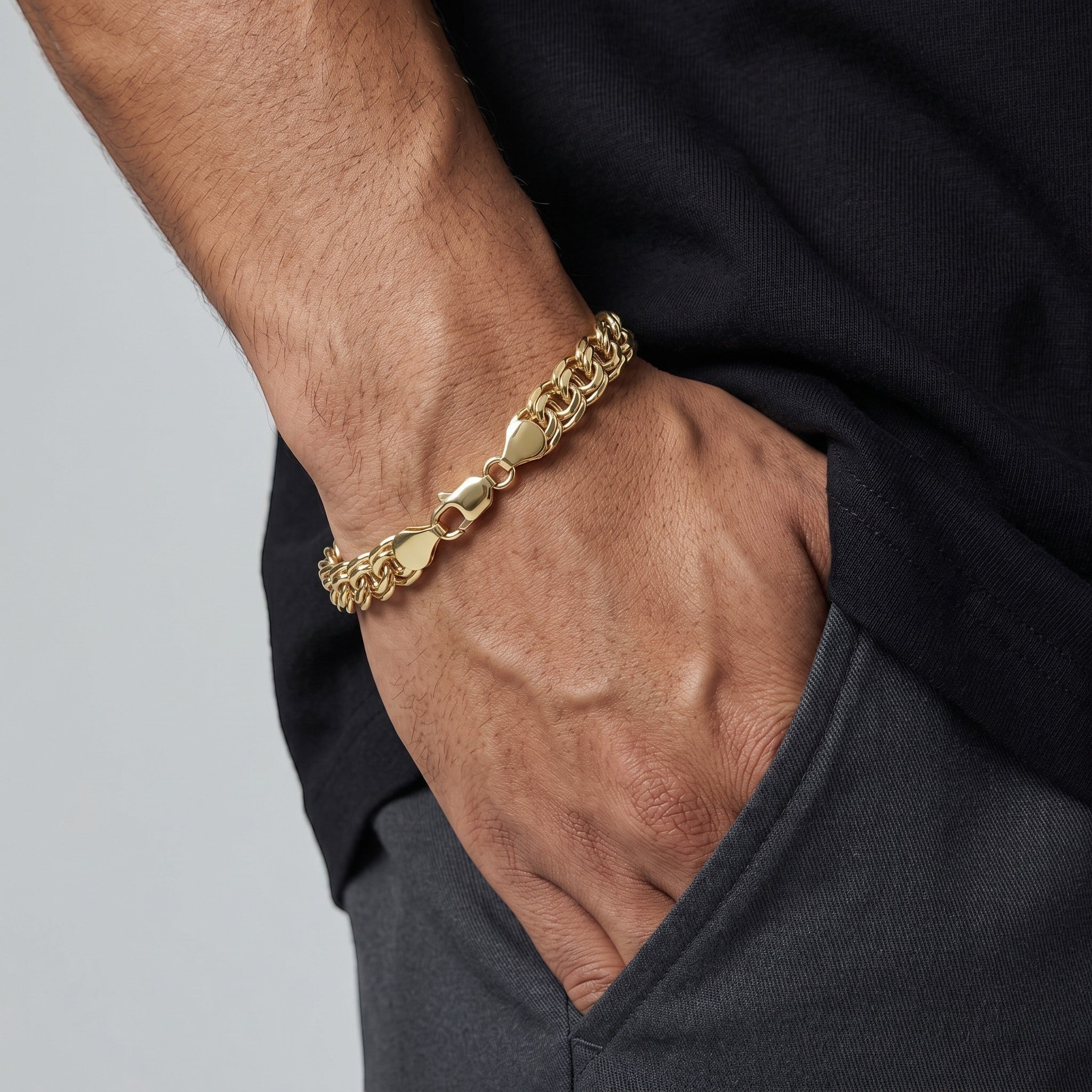 Pulsera de eslabones estilo chino en oro laminado 18k de El Rey Joyero, gruesa y brillante en la muñeca de un hombre.