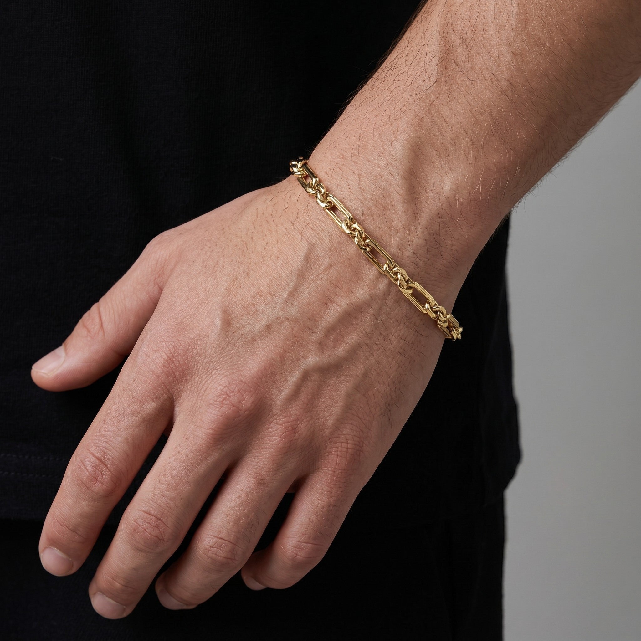 Pulsera estilo Fígaro de El Rey Joyero en oro laminado 18k de 5mm, lucida en la muñeca de un hombre.