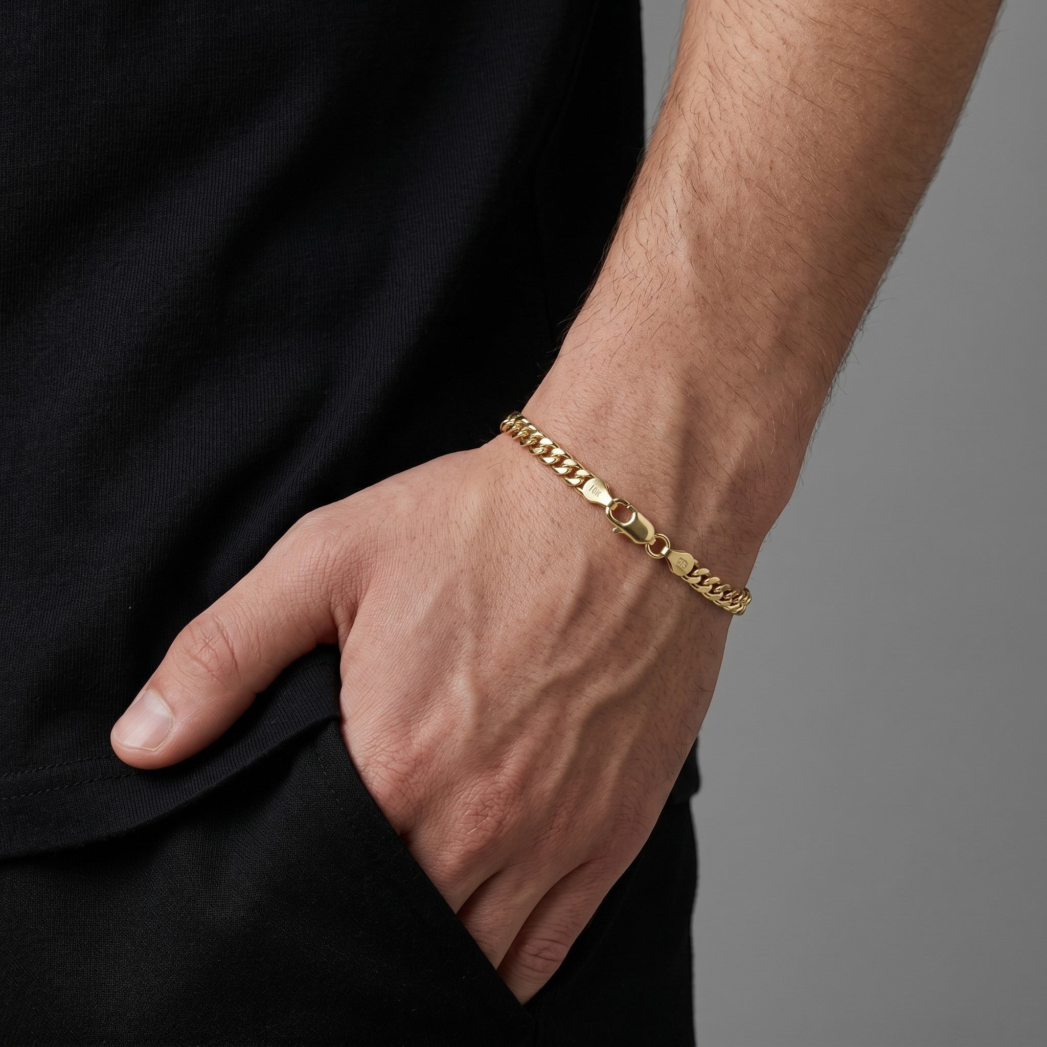 Pulsera Mónaco delgada de oro laminado 18k de El Rey Joyero en la muñeca de un hombre con camiseta negra