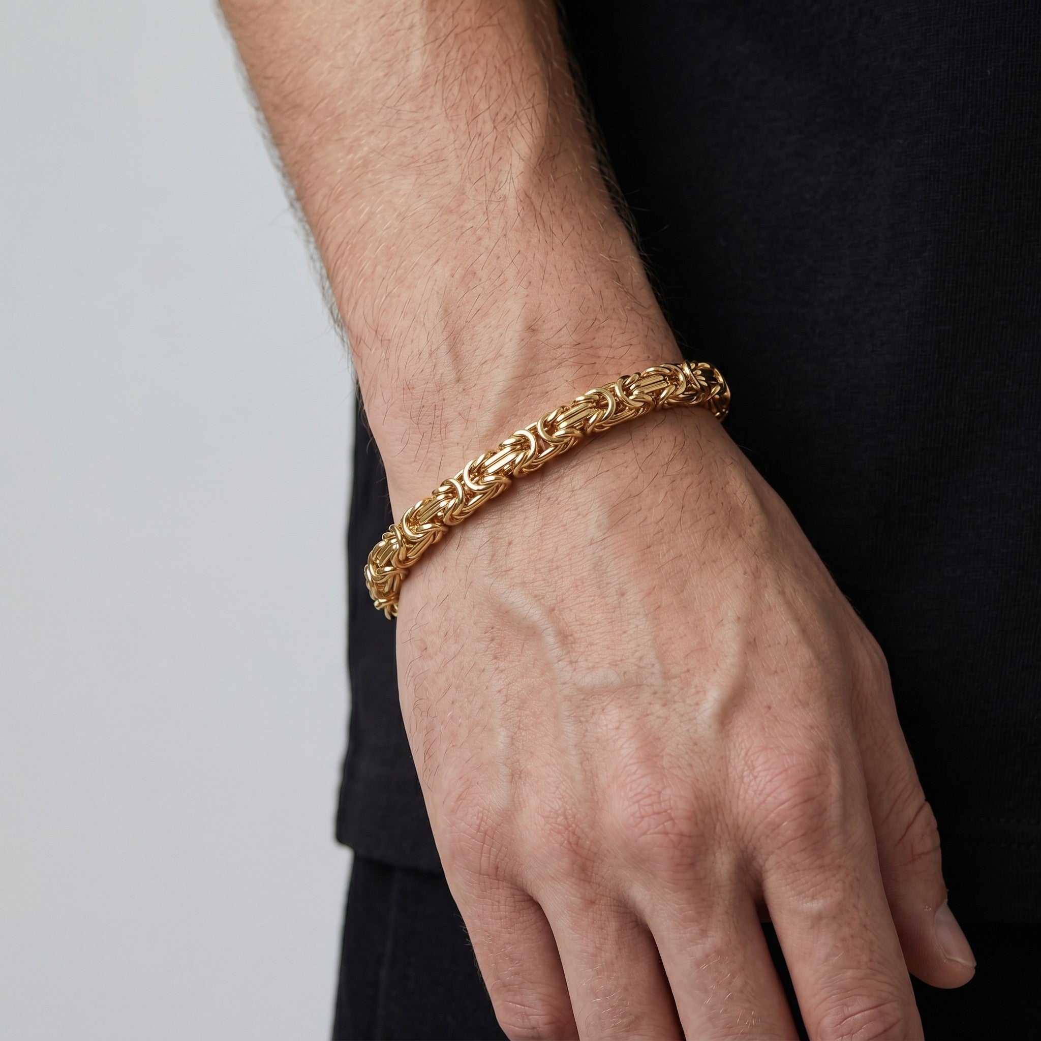 Pulso tejido romano de El Rey Joyero en oro laminado 18k con eslabones bizantinos de 6 mm en la muñeca de un hombre.
