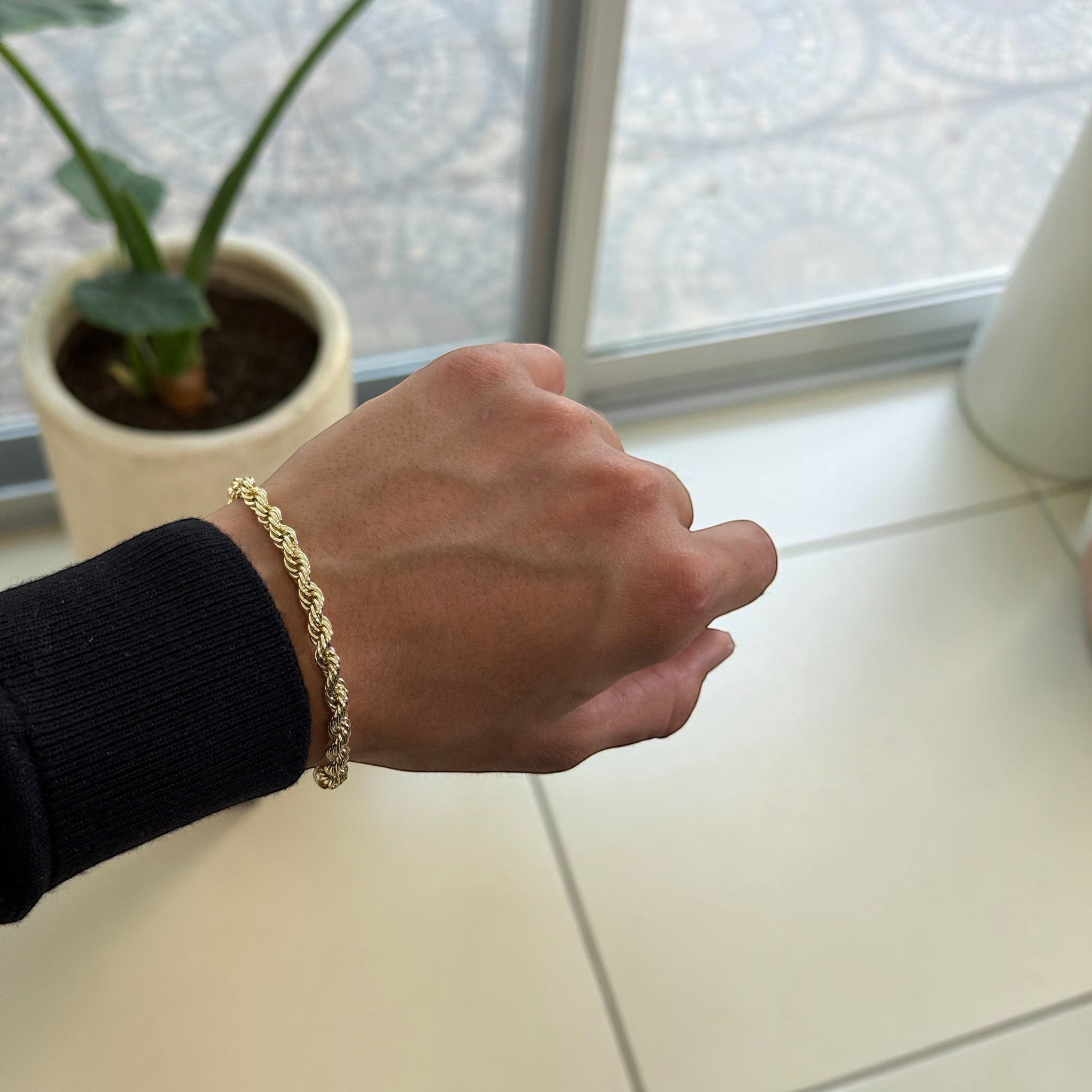 Pulso torzal delgado de El Rey Joyero en oro laminado 18k con eslabones trenzados brillantes en la muñeca de un hombre.